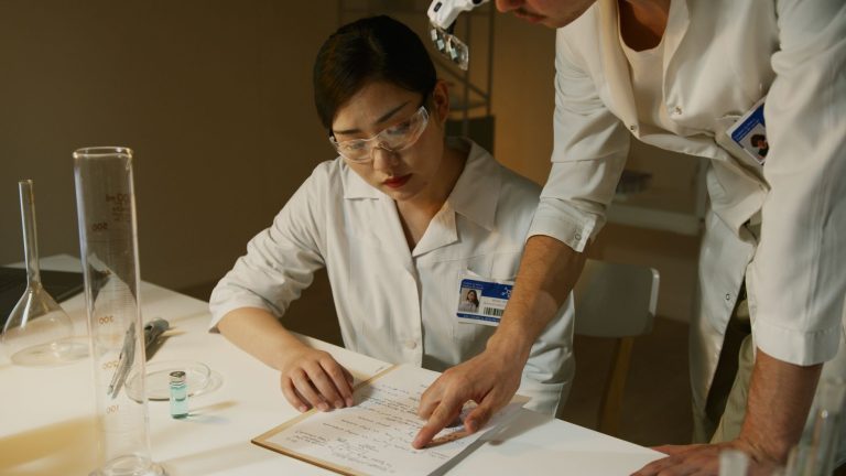 Pesquisadores de jaleco analisam anotações e materiais durante um estudo em laboratório.
