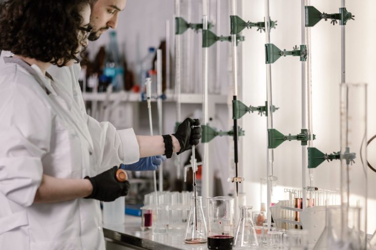Pesquisadores de jaleco trabalham com tubos de ensaio em um laboratório moderno.