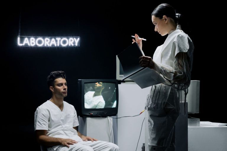 Dois cientistas analisam dados em um laboratório futurista enquanto acompanham um participante de pesquisa.