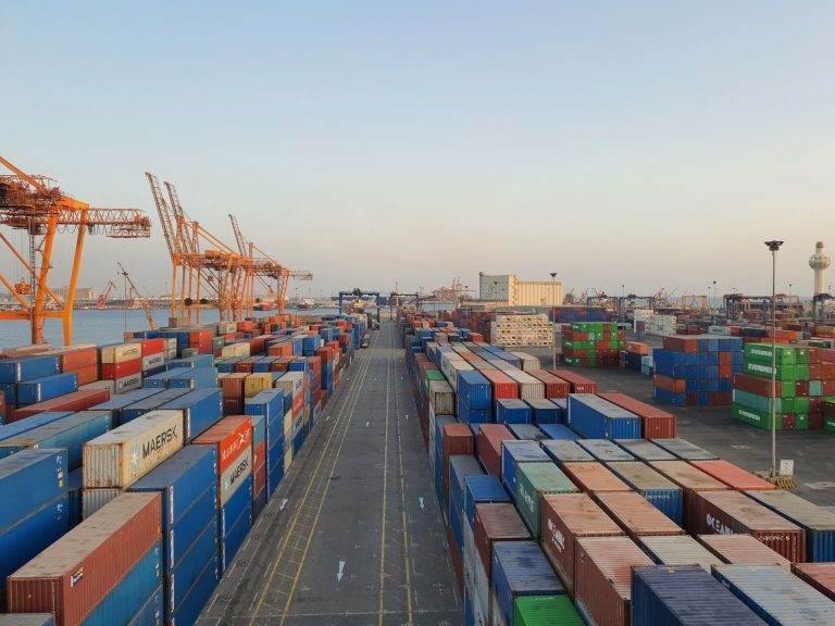 Brasil promulga acordo Mercosul-EFTA e prepara empresas para novas regras de comércio exterior Porto movimentado com contêineres coloridos e estruturas de carga ao amanhecer.