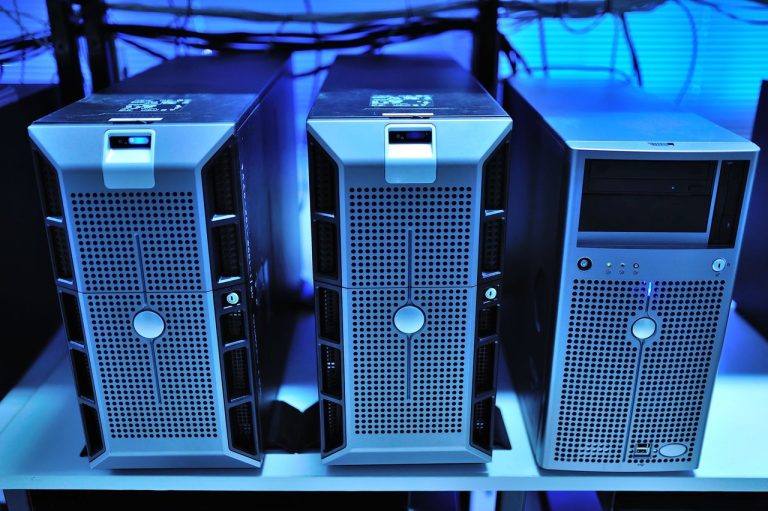 Close de racks de servidores modernos em um data center, com luzes azuis e equipamentos de processamento.