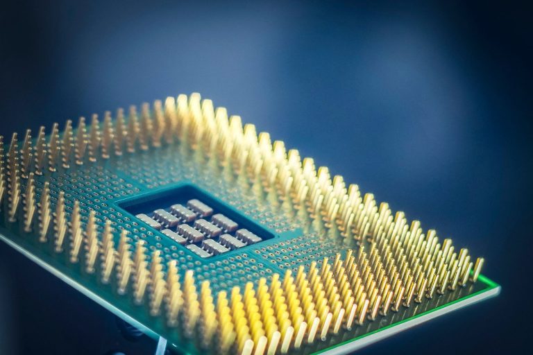 Close de um chip de processamento com contatos dourados sobre fundo azul