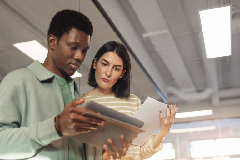 Dois profissionais colaboram em um projeto usando um tablet em um escritório moderno.