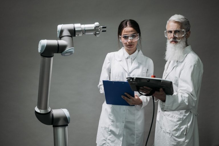 Hub de IA aproxima indústrias brasileiras de startups e pesquisadores Dois pesquisadores observam um braço robótico em um laboratório de tecnologia.