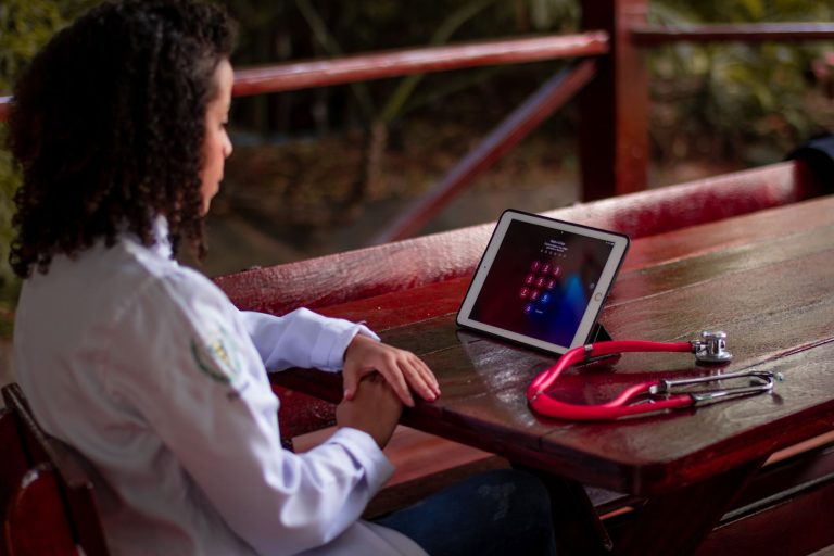 Edital do Ministério da Saúde define etapas para projetos de saúde digital no SUS Profissional de saúde usa um tablet ao ar livre, com um estetoscópio apoiado sobre o ombro.