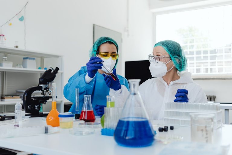 Duas cientistas analisam amostras em um laboratório equipado.