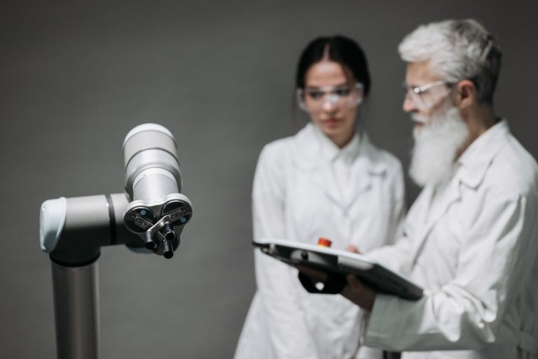 Pesquisadores de jaleco analisam equipamentos robóticos em um laboratório.